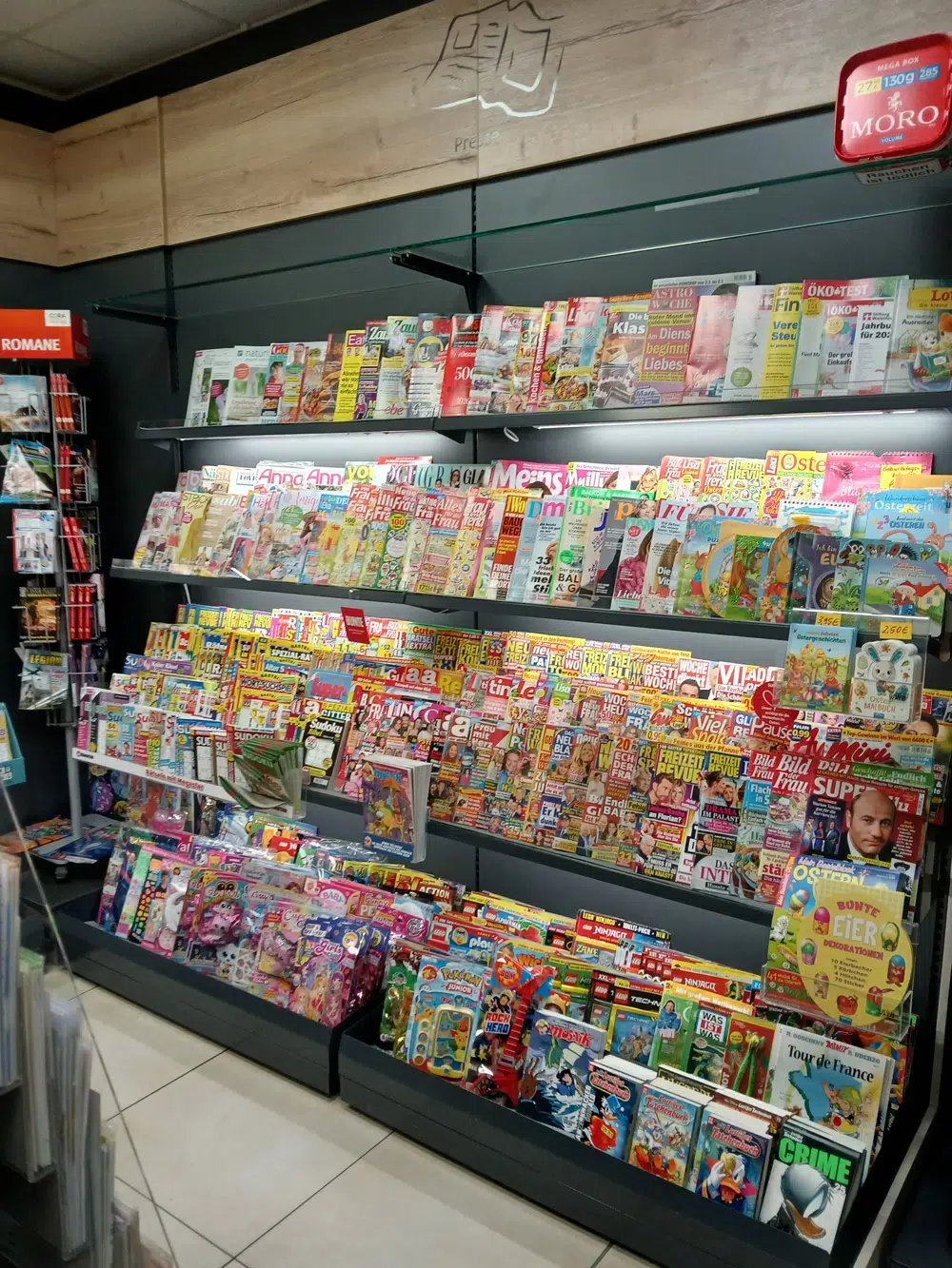 Ein gut gefuelltes Zeitschriftenregal mit bunten Magazinen in einem Geschaeft