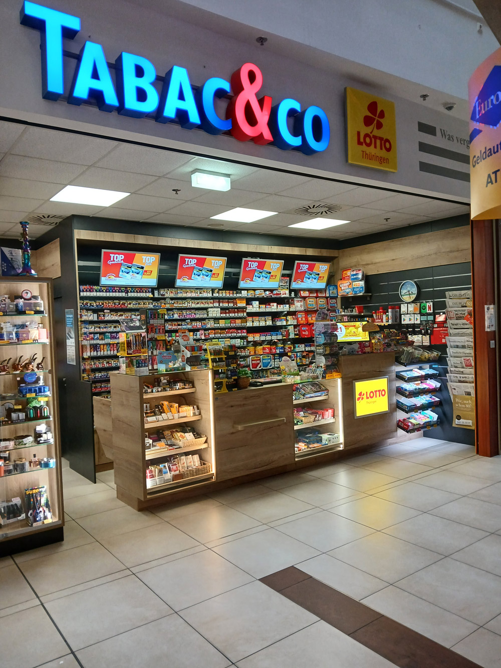 Ein moderner Kiosk mit farbenfrohen Regalen voller Snacks, Zigaretten und Zeitschriften